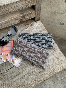 Detailed embroidery of leaf patterns on long linen fabric pouches with metal zippers