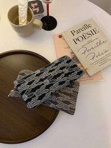 Close-up of linen pouches with woven rabbit patterns and gold zippers on a wooden tray