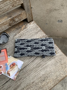Detail of black cotton glasses pouch with rabbit embroidery on a rustic wooden background