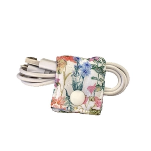 Floral fabric cable organizer with snap button holding a white USB data wire