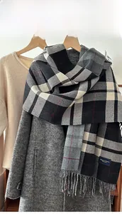 Detail of classic plaid scarf with fringe and elegant tag on wool coat