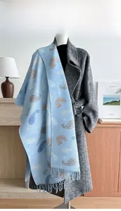 Detail of light blue paisley knit scarf with long tassels draped on a dark wool coat