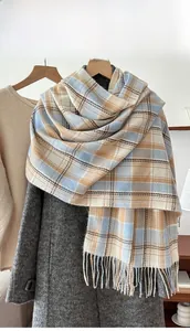 Detail of blue and beige plaid cashmere-like scarf with fringe on a wooden hanger