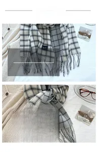 Close-up of thick plaid tassel scarf in grey, cream, and black soft cashmere-like fabric