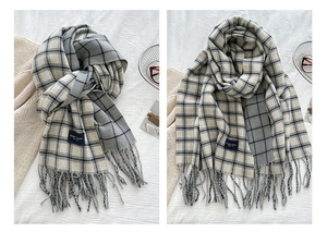Detailed view of beige and grey plaid scarf with soft fringe edges and woven brand tag