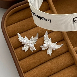Boucles d'oreilles papillon en argent brossé avec perles sur boîte à bijoux en velours