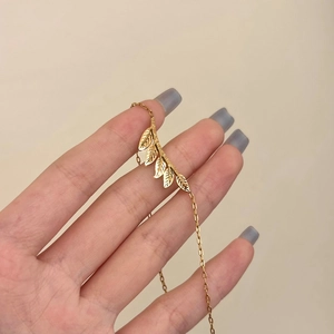 Elegant gold leaf branch necklace with detailed texture and minimalist delicate thin chain
