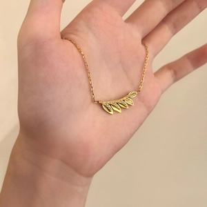 Close-up of golden leaf pendant with textured veins on fine O-chain necklace