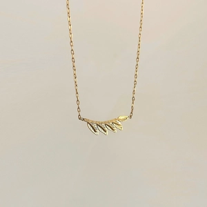 Detail of gold leaf necklace showing frosted texture and delicate cable chain design