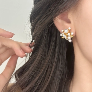 Elegant gold pearl cluster earrings with sparkling cubic zirconia on a model's ear