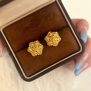 Close-up of golden rose cluster earrings in a velvet jewelry box on faux fur