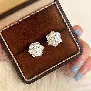Close-up of elegant silver rose cluster earrings with detailed floral relief on velvet