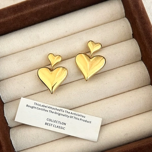 Polished gold heart drop earrings displayed in a luxury brown velvet jewelry box