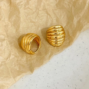Détail macro de boucles d'oreilles créoles dorées avec texture en spirale