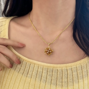 Chic gold starburst pendant necklace with white cubic zirconia worn by a female model
