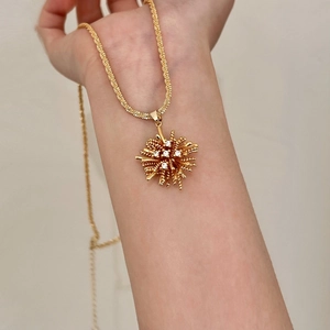 Close-up of a gold fireworks pendant necklace with zircon crystals on a female wrist