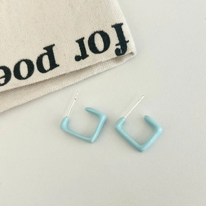 Macro detail of minimalist light blue square geometric earrings with smooth enamel finish