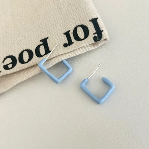 Close-up of light blue square geometric earrings with smooth enamel finish and silver studs