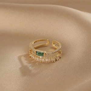 Double-layered open ring with emerald green zircon and crystals on champagne silk background