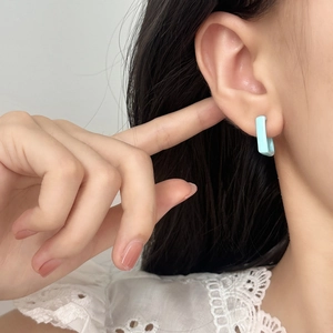 Minimalist light blue rectangular enamel hoop earrings shown worn on the ear