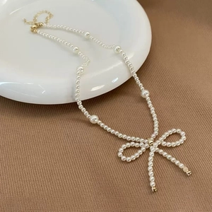 Elegant white pearl necklace with central large beads and a delicate pearl bow pendant