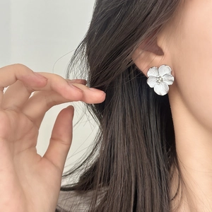 Elegant silver flower stud earrings with pearl centers worn on a female model