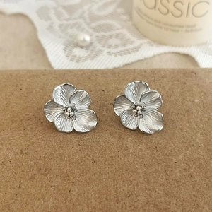 Macro detail of silver flower earrings with small white pearls and crystals