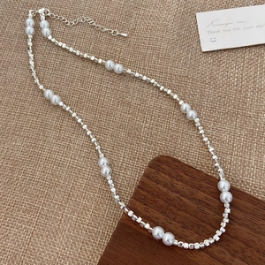 Dettaglio di perle bianche e cubi d'argento con chiusura a moschettone regolabile