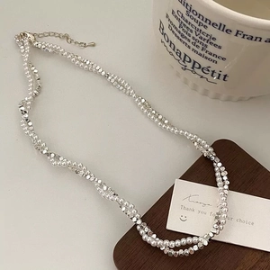 Collana a doppio strato con perle bianche e perle argentate sfaccettate su vassoio in legno