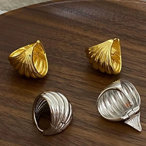 Textured gold and silver croissant earrings displayed on a rustic wooden tray