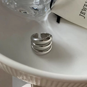Close-up of three-layer silver polished open ring on a white ceramic tray display