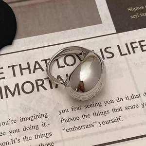 Detailed top view of a chunky silver water-drop ring on vintage newspaper background