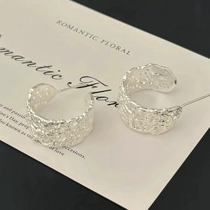 Close-up of S925 silver C-shape stud earrings with hollow lace texture on display card