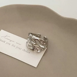 Glossy silver liquid lava open ring with irregular ripple texture on minimalist background