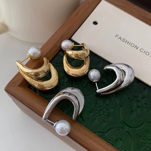 U-shaped gold and silver earrings with pearl backings in a luxury jewelry box