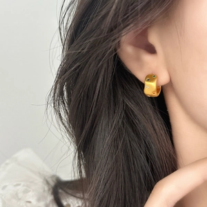 Orecchini geometrici in oro spazzolato con zirconi colorati a forma di stella su modella