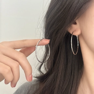 Minimalist silver geometric hoop earrings for women shown worn on a model's ear