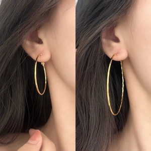 Detail of gold geometric hoop earrings with textured finish shown on a model
