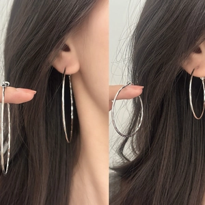 Detail of large silver textured hoop earrings featuring hammered finish on the metal surface
