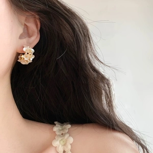 Boucles d'oreilles fleurs mates blanches élégantes avec perles dorées sur modèle