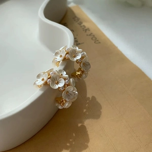 Boucles d'oreilles fleurs en C élégantes avec pétales blancs et perles sur plateau en céramique