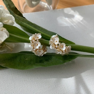 Boucles d'oreilles fleurs en C avec pétales blancs et perles sur fond de fleurs fraîches