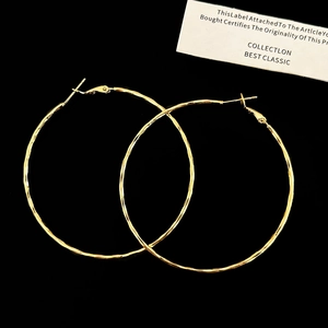 Detailed view of large gold hoop earrings with textured hammered finish and pin closure
