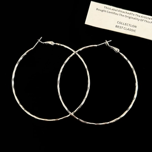 Detailed macro view of large silver-tone hammered hoop earrings with a textured metal finish