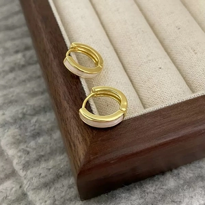 Élégantes boucles d'oreilles créoles dorées avec émail blanc sur plateau à bijoux