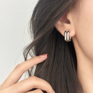 Minimalist silver triple-layered U-shaped hoop earrings on a model side view