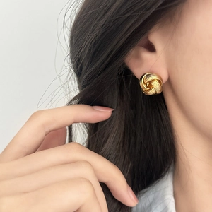 Elegant gold knot earrings with twisted texture worn by a model for a chic daily look