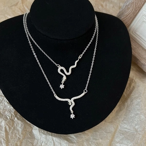 Elegant silver snake pendant necklace set with cubic zirconia on black velvet bust