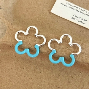 Detail of sweet blue enamel flower stud earrings on textured brown background
