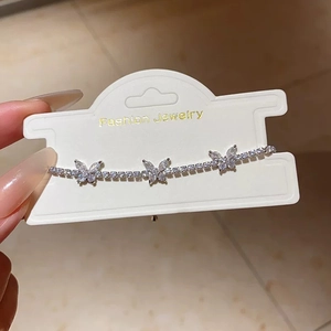 Detail shot of silver tennis bracelet with sparkling zirconia butterfly charms on card